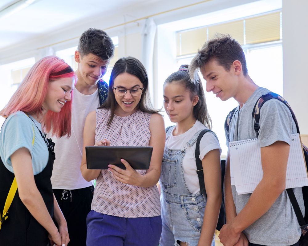 Grupo de estudiantes y profesora mirando la pantalla de una tablet. Concepto de formación.