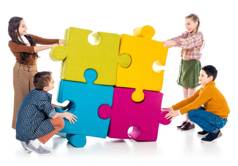 Niños encajando piezas gigantes de un puzzle.