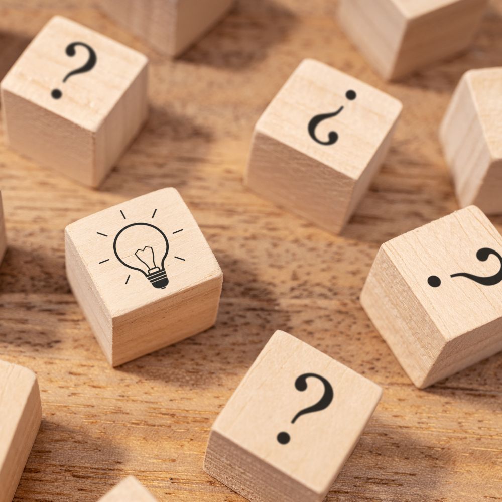 Bloques de madera con interrogaciones y bombilla dibujadas en cada uno de ellos. Concepto de ideas creativas.